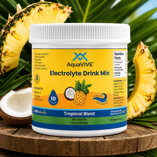 A tub of AquaVIVE Electrolyte Drink Mix in Tropical Blast flavor, styled on a wooden surface with sliced pineapples and a coconut half in the background.